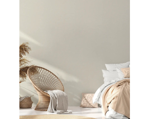 Ljust utformat sovutrymme med rottingstol och dubbelsäng.