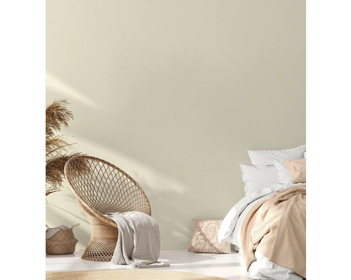 Ljust sovrum med rottingfåtölj, säng och dekorativa textilier för en mysig atmosfär