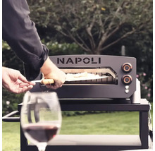 Napoli pizzaugn på ett bord, med en person som skjuter in en pizza med en pizzaspade