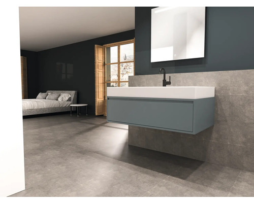 Modernt badrum med tvättställ, spegel och säng i bakgrunden