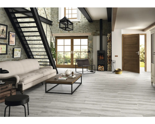 Ljust vardagsrum med stentrappa, soffa, träbord, vedspis och trägolvplattor med träutseende.