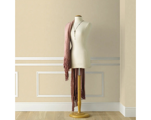 Skräddarbyst med sjal och halsband framför en vägg med dekorlister