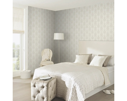 Sovrum med säng, fåtölj, golvlampa och mönstrad tapet