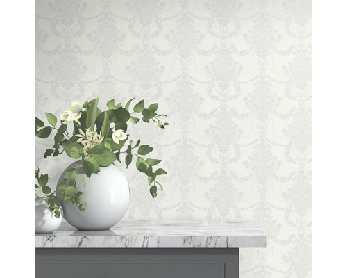 Tapet med blommönster bakom vita vaser på ett bord.