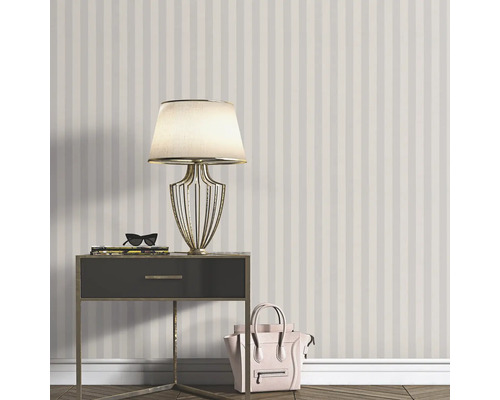 Scen med randig tapet, sängbord, lampa och handväska