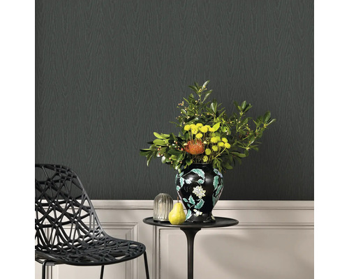 Dekorativt vardagsrum med svart designtapet i trälook, ett sidobord med blomvas och en designstol.