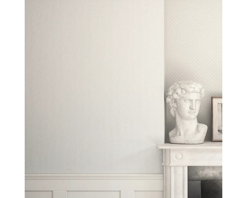 Ljus vägg med mönstrad tapet och dekoration på en spiselkrans