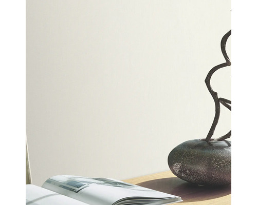 Ljus vägg med vas, grenar och bok på ett bord.