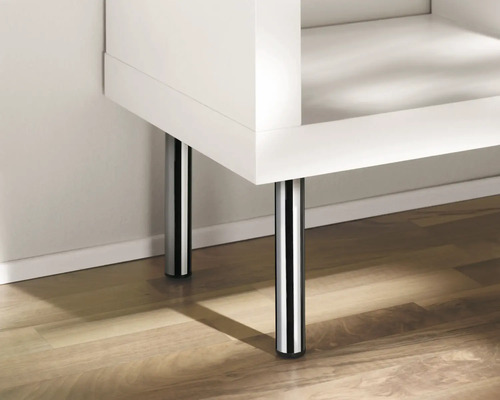 Detaljbild av en vit möbel med kromade ben på ett trägolv