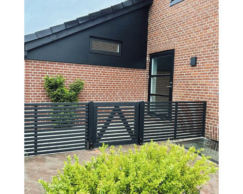 Exteriörvy av ett hus med tegelfasad och ett staket med grind.