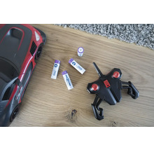 Leksaksbil med fjärrkontroll och batterier på ett trägolv