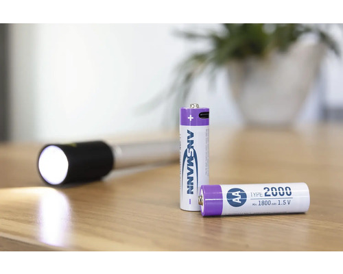 Två Ansmann AA-batterier och en ficklampa på ett bord