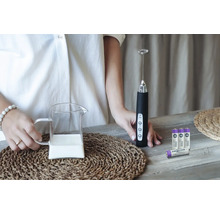 Mjölkskummare med mjölkkanna och batterier på ett bord