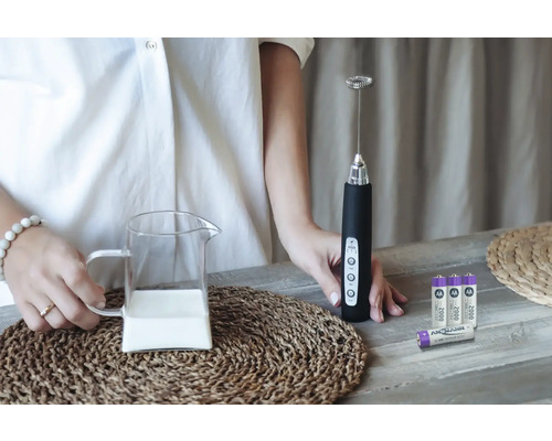 Mjölkskummare med mjölkkanna och batterier på ett bord