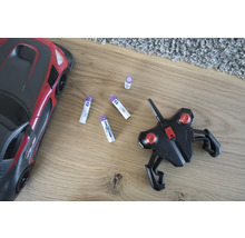 Leksaksbil, fjärrkontroll och batterier på ett trägolv