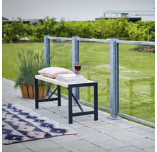 Bänk med metallram, kudde, böcker och vinglas på en terrass