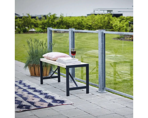 Bänk med metallram, kudde, böcker och vinglas på en terrass