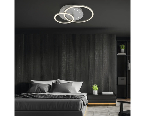 Sovrum med ringformad taklampa, säng, nattduksbord och bokhylla