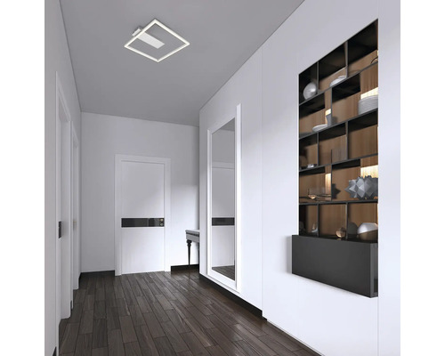 Ljus hall med fyrkantig taklampa, spegel och hylla.