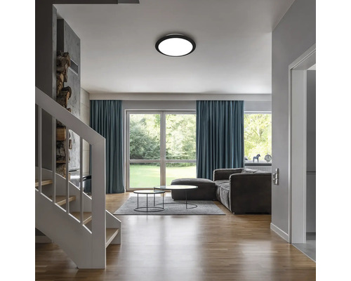 Vardagsrum med taklampa, soffa, fönster och trappa