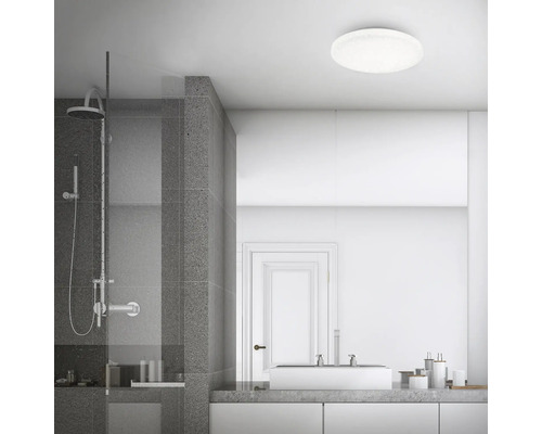 Modernt badrum med dusch, handfat och rund taklampa