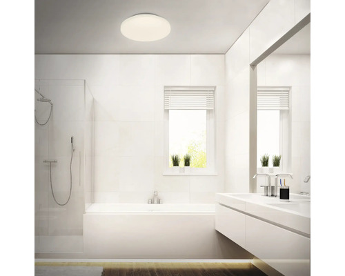 Ljust badrum med dusch, badkar, handfat och rund taklampa