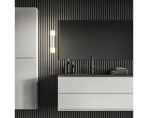 Modernt badrum med tvättställ, spegelskåp, utanpåliggande lampa och handdukar framför en vägg med randigt mönster.