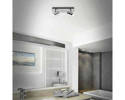 Badrum med två spotlights i taket, spegel och handfat.