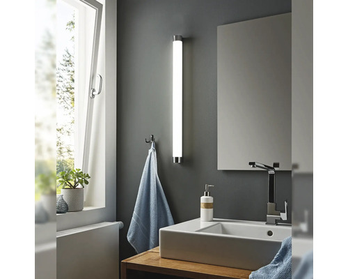 Modernt badrum med handfat, spegel och stavformad vägglampa