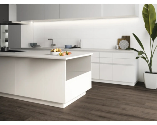 Ljust kök med köksö, diskho och trägolv.