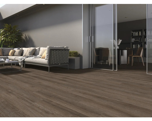 Terrass med mörkt trägolv, soffa och utsikt över ett rum med en bokhylla