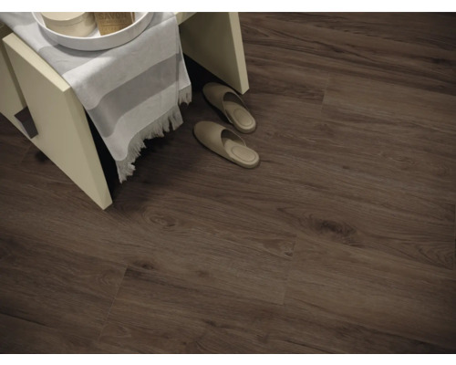 Interiörbild av ett rum med laminatgolv i träimitation, en liten pall och tofflor.