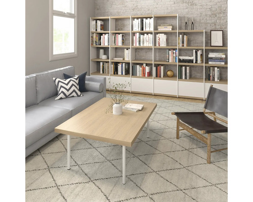 Vardagsrum med soffa, soffbord, bokhylla och fåtölj på en mönstrad matta