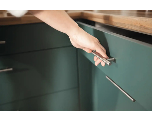 Närbild av en person som öppnar ett köksskåp med ett stånghandtag