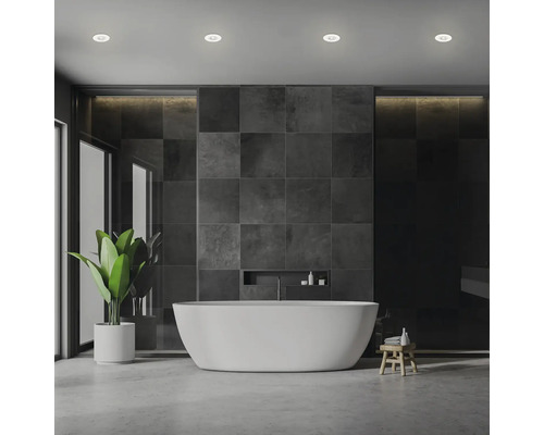 Modernt badrum med fristående badkar, grå kakel och krukväxt