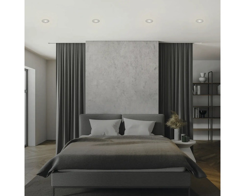 Sovrum med säng, gardiner, bokhylla och infällda takspotlights