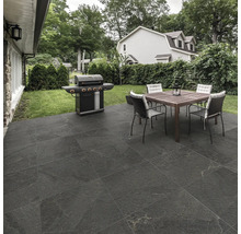 Uteplats med grill, bord och stolar i trädgården