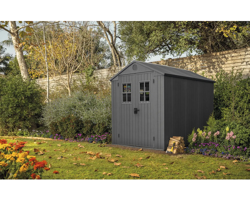 Trädgårdsskjul i trädgården med vedstapel