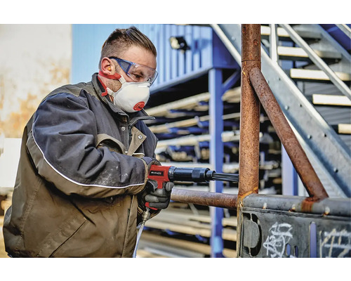 Man med nålhammare som avlägsnar rost från metall