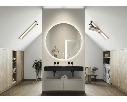 Ljust badrum på vinden med rund spegel med belysning, handfat, takfönster och inbyggda skåp