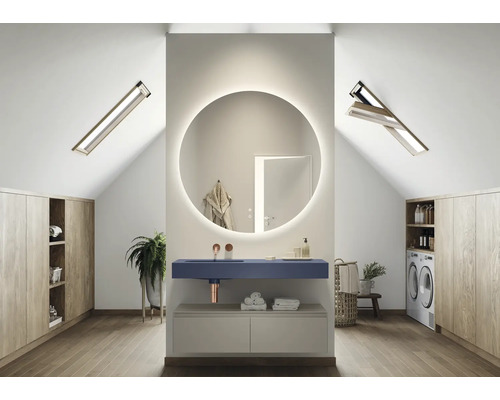 Ljust badrum på vinden med rund spegel med belysning, tvättställ, tvättmaskin och inbyggda skåp