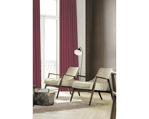 Vardagsrum med två fåtöljer, golvlampa och vinröda gardiner