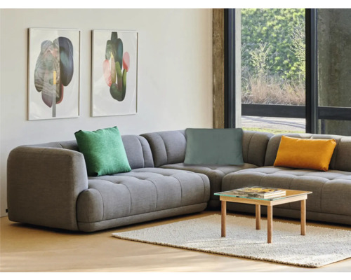 Vardagsrum med grå hörnsoffa, kuddar, soffbord och väggmålningar