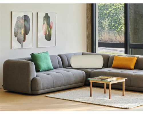 Vardagsrum med grå hörnsoffa, kuddar, tavlor och soffbord