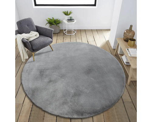 Inredningsscen med rund grå matta, fåtölj och sidobord