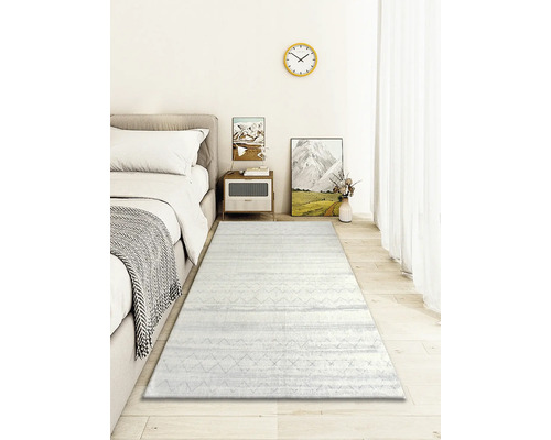 Sovrum med säng, sängbord, dekoration och en ljus matta med mönster.