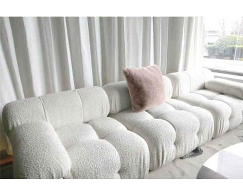 Vit modulsoffa av bouclé med kudde