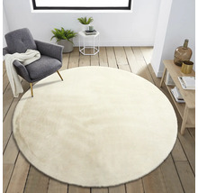 Beige, rund matta i vardagsrummet bredvid en fåtölj och ett bord
