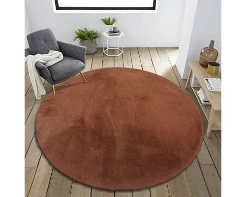 Rund fuskpältsmatta i ett ljust, modernt rum med en stol och sidobord.