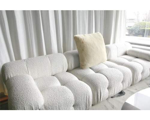 Modulsoffa med kudde framför ett fönster med gardiner